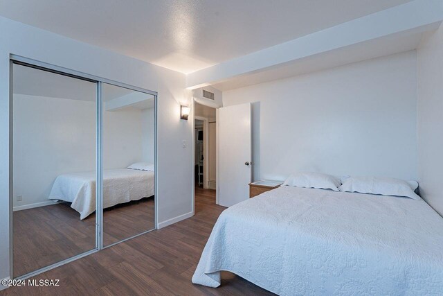 bedroom with dark hardwood / wood-style floors and a closet