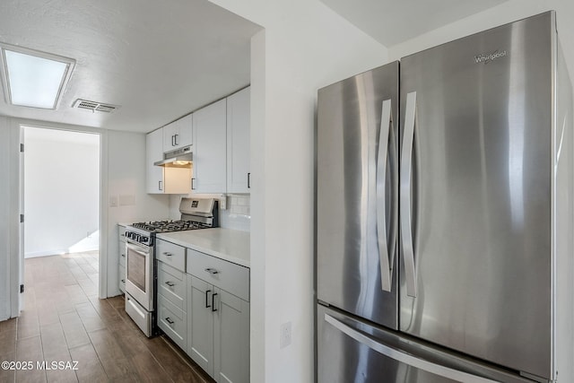 kitchen with backsplash, dark wood-type flooring, white cabinets, and appliances with stainless steel finishes