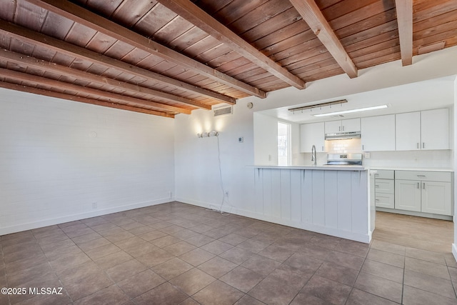 unfurnished living room with light tile patterned floors, wood ceiling, sink, and beamed ceiling