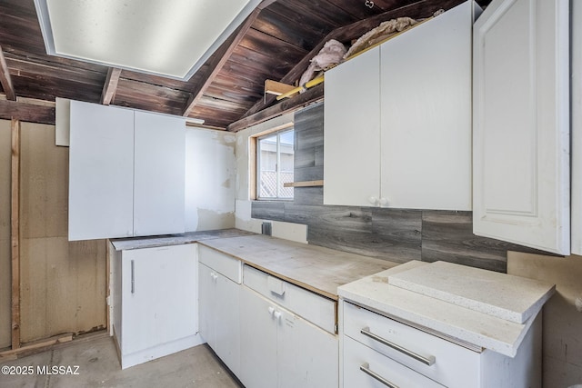 kitchen with white cabinetry, wood ceiling, and backsplash