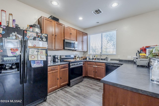 kitchen featuring light wood-type flooring, sink, and black appliances