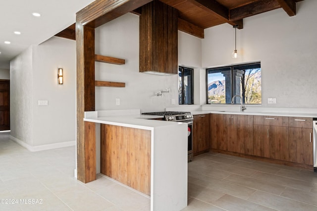 kitchen with kitchen peninsula, gas range, sink, light tile patterned floors, and beam ceiling