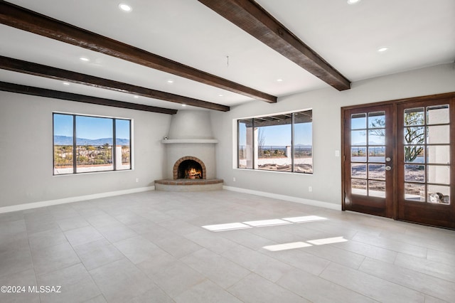 unfurnished living room featuring a large fireplace, a mountain view, french doors, and beam ceiling