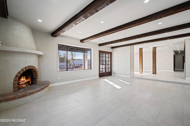 unfurnished living room featuring a fireplace, french doors, and beam ceiling