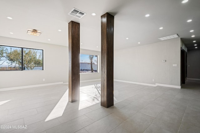 spare room with light tile patterned flooring and decorative columns