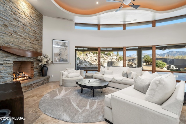 living room with a mountain view, a fireplace, ceiling fan, and a high ceiling