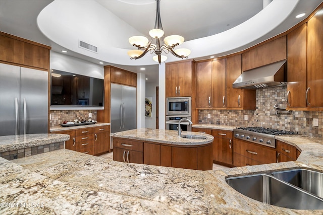 kitchen featuring pendant lighting, built in appliances, light stone counters, and extractor fan