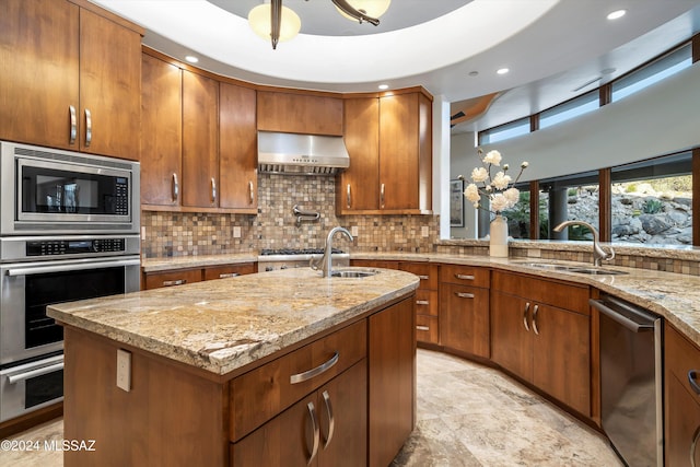 kitchen with appliances with stainless steel finishes, a center island with sink, sink, and exhaust hood