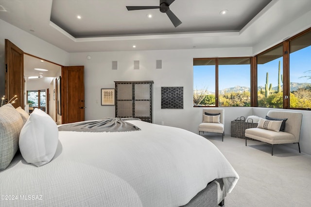 bedroom with carpet flooring, ceiling fan, a mountain view, and a tray ceiling