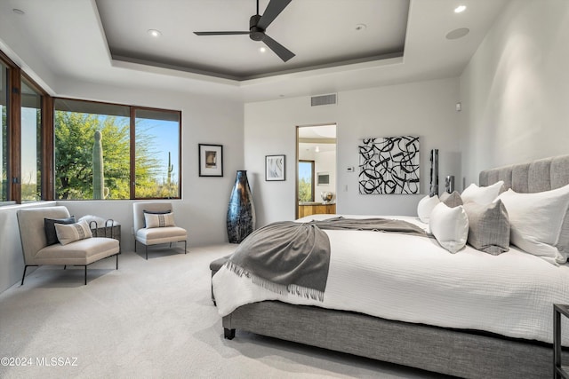 bedroom with a tray ceiling, ceiling fan, and carpet flooring