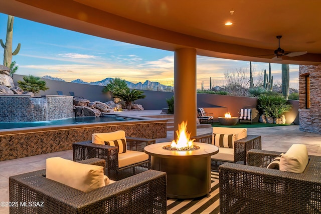 patio terrace at dusk featuring a mountain view and an outdoor living space with a fire pit