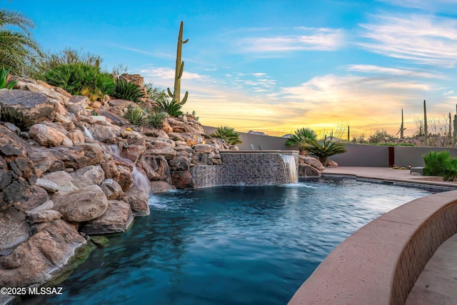 pool at dusk featuring pool water feature