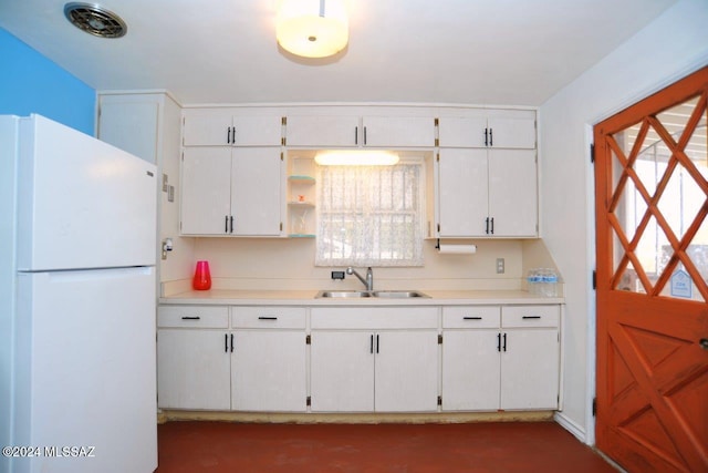 kitchen with white cabinetry, sink, and white refrigerator