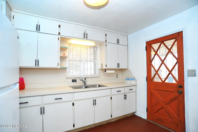 kitchen with white refrigerator, white cabinetry, and sink