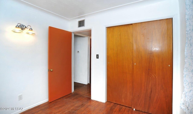 unfurnished bedroom featuring a closet and dark wood-type flooring