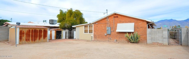 rear view of property with a mountain view, a storage unit, and cooling unit