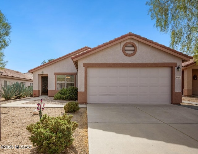 view of front of home with driveway, a tiled roof, a garage, and stucco siding