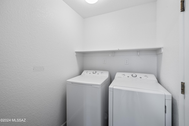 clothes washing area featuring a textured wall, laundry area, and washer and dryer