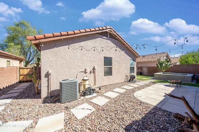 back of house featuring a patio area, a fenced backyard, central AC, and stucco siding