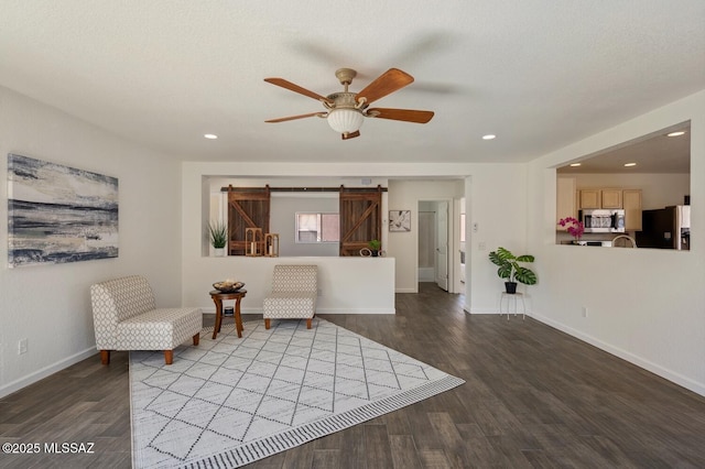 unfurnished room with recessed lighting, a barn door, a ceiling fan, wood finished floors, and baseboards