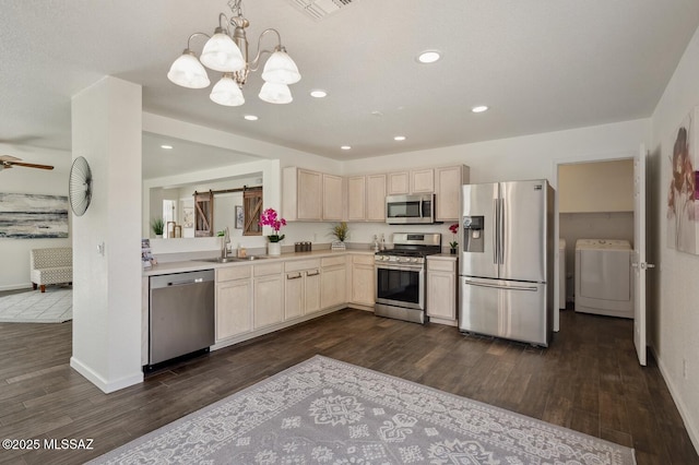 kitchen with a barn door, stainless steel appliances, a sink, light countertops, and washer / clothes dryer