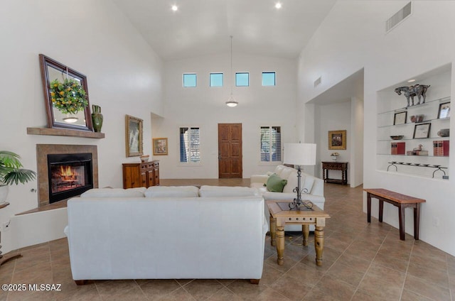 living room featuring built in shelves, lofted ceiling, light tile patterned flooring, and a tile fireplace