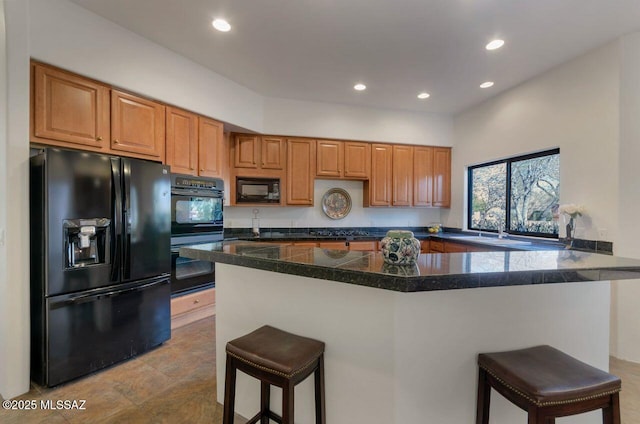 kitchen with kitchen peninsula, sink, a breakfast bar area, and black appliances