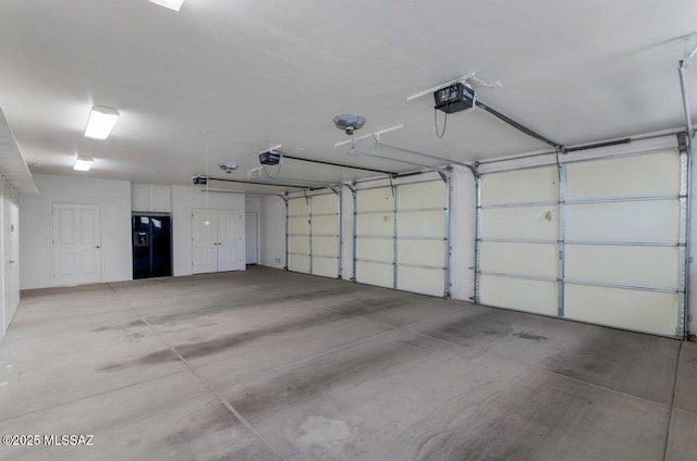 garage with a garage door opener and black fridge with ice dispenser