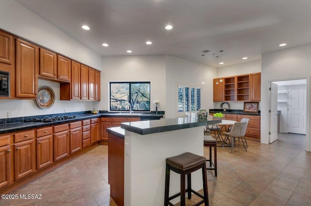 kitchen with sink, a kitchen breakfast bar, a center island, black appliances, and light tile patterned flooring