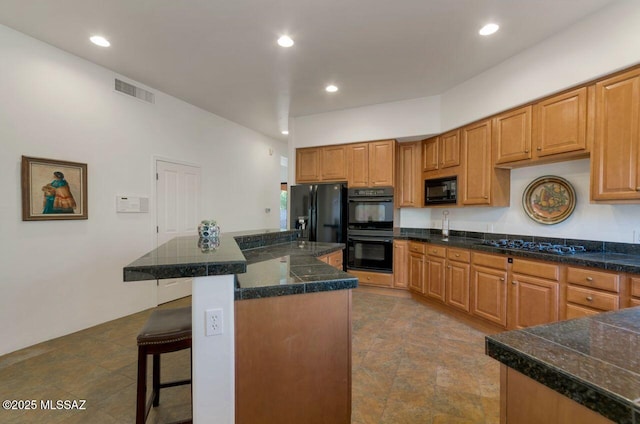 kitchen with a breakfast bar, a center island, and black appliances