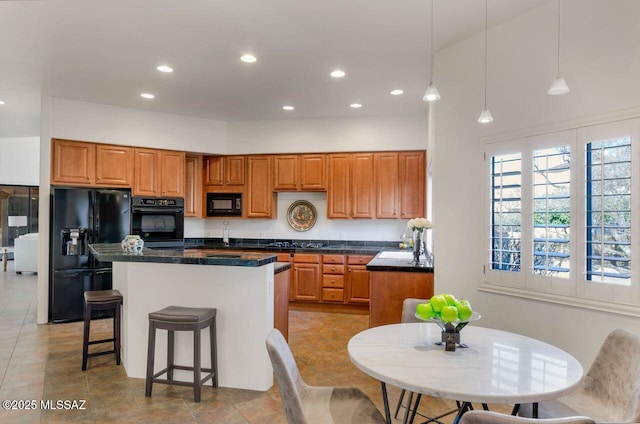 kitchen with pendant lighting, a breakfast bar area, black appliances, and a center island