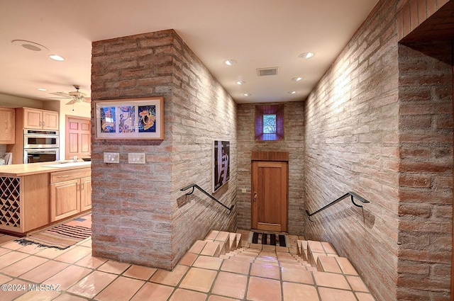 interior space with sink, ceiling fan, light tile patterned floors, light brown cabinetry, and stainless steel double oven