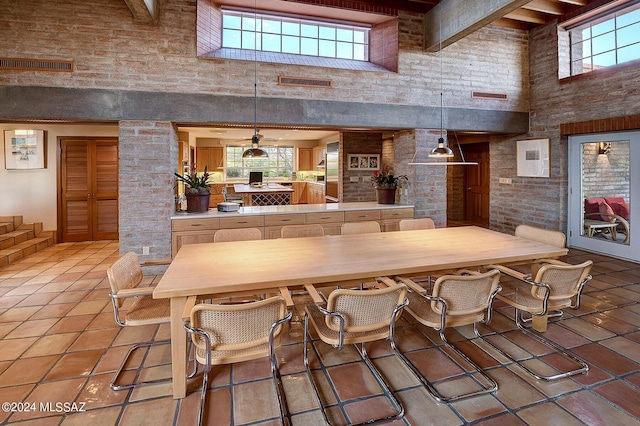 interior space featuring a kitchen breakfast bar, tile patterned flooring, a towering ceiling, beamed ceiling, and decorative light fixtures