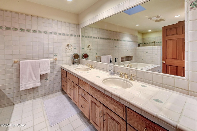 bathroom featuring vanity, tile patterned floors, tile walls, and a bathing tub