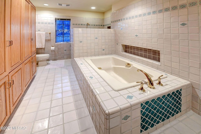 bathroom featuring toilet, tile patterned floors, tile walls, and tiled tub