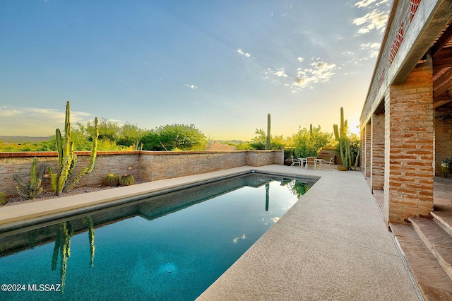 pool at dusk featuring a patio