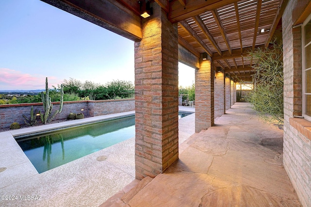 pool at dusk featuring a patio area