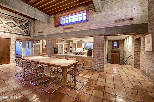 dining space with tile patterned floors, beam ceiling, ornate columns, and a high ceiling