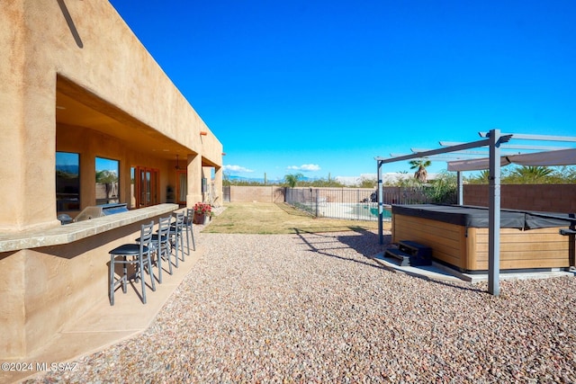 view of yard featuring a pergola, a patio area, an outdoor bar, and a hot tub