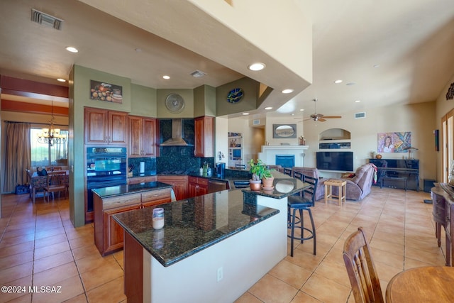 kitchen featuring wall chimney exhaust hood, oven, decorative backsplash, and light tile patterned floors