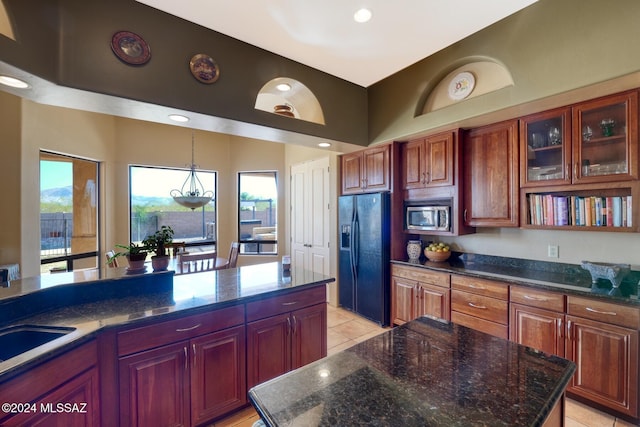 kitchen featuring black fridge with ice dispenser, a kitchen island, stainless steel microwave, and dark stone counters