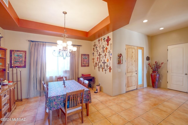 dining area with light tile patterned floors, a tray ceiling, and a chandelier