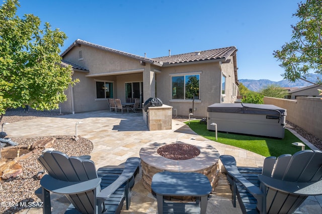 rear view of house featuring a mountain view, a patio, a hot tub, and a fire pit