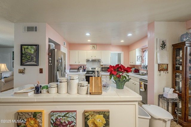 kitchen with tile countertops, white cabinetry, sink, and appliances with stainless steel finishes