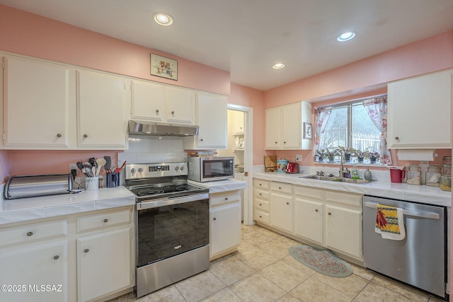 kitchen featuring appliances with stainless steel finishes, white cabinetry, and sink