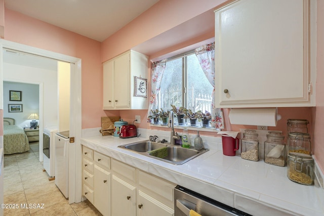 kitchen with tile countertops, washer and dryer, light tile patterned flooring, and sink