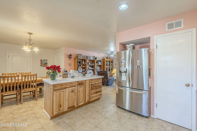 kitchen with decorative light fixtures, stainless steel fridge, a kitchen island, and ceiling fan with notable chandelier