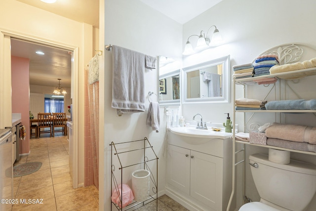 bathroom featuring tile patterned flooring, vanity, an inviting chandelier, and toilet