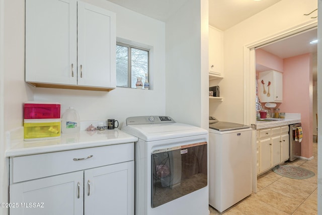 laundry room with cabinets, sink, separate washer and dryer, and light tile patterned flooring