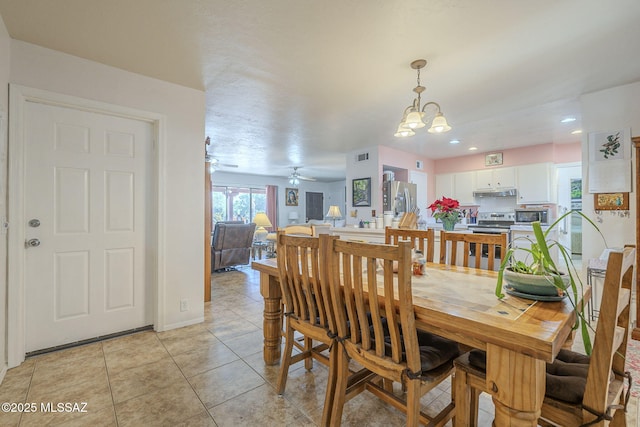 tiled dining area with ceiling fan with notable chandelier